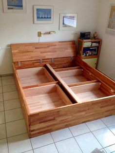 a wooden bed frame with two drawers on each side and an open drawer in the middle