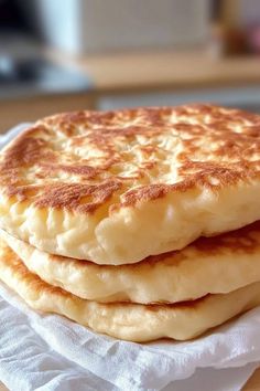 three pancakes stacked on top of each other on a white paper towel in front of a wooden table