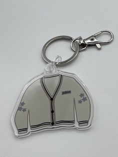 a white jacket shaped keychain with a black and grey design on the front