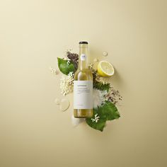 a bottle of white wine surrounded by flowers and leaves on a yellow background with an empty label