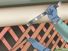 a person wearing blue gloves and holding a wrench in their hand while working on a wall