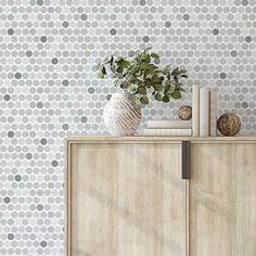 a white vase sitting on top of a wooden cabinet next to a wall with polka dots