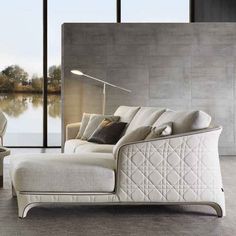 a white couch sitting in front of a window next to a lamp on a table