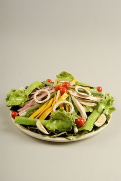 a white plate topped with lettuce and other vegetables on top of a table