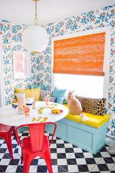 a dining room with colorful walls and flooring is pictured in this image, there are two cats sitting on the table