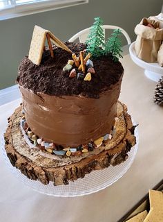 a chocolate cake sitting on top of a white table next to cookies and crackers