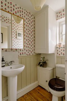 a bathroom with a toilet, sink and mirror next to a wooden flooring area