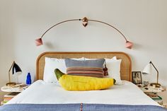 a bed with two lamps on either side and a banana pillow on the headboard