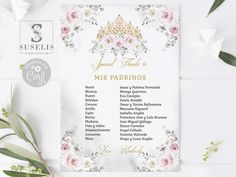 a white and gold wedding program with pink flowers on it, surrounded by greenery