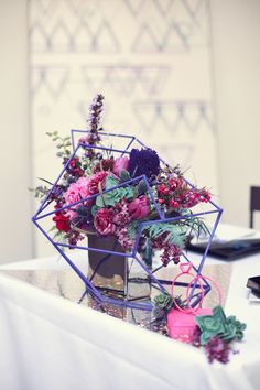 a vase filled with lots of flowers on top of a white tablecloth covered table