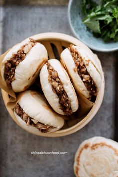 a wooden bowl filled with sandwiches next to a cup of soup and some other food