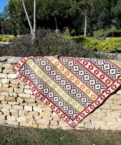 a large piece of art sitting on top of a stone wall next to grass and trees