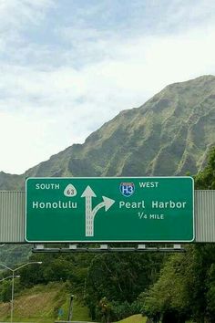 a highway sign showing the direction to honolulu and pearl harbor, with mountains in the background