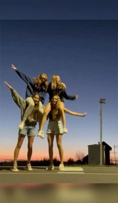 four young women are posing for the camera in front of an empty parking lot at sunset