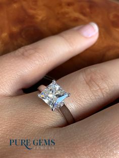 a woman's hand with a diamond ring on her finger, showing the center stone