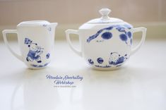 two blue and white teapots sitting on top of a table next to each other