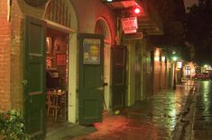 an alleyway with green doors and brick buildings at night