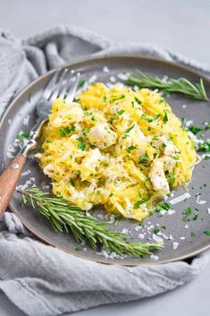 scrambled eggs with chicken and herbs on a gray plate next to a wooden utensil