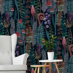 a chair and table in front of a wallpaper with plants on the sideboard