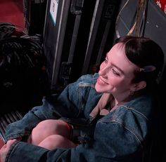 a woman sitting on the ground next to some suitcases