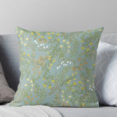 a green and yellow floral pattern on a blue background throw pillow sitting on a couch