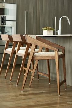 three wooden chairs sitting on top of a hard wood floor next to an island in a kitchen