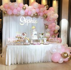 a table with balloons, cake and cupcakes on it