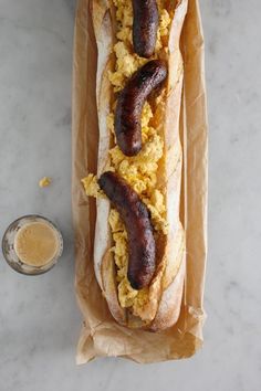 two hot dogs on buns with scrambled eggs and sausage