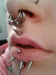 a close up of a person with many piercings on their face and nose,