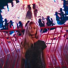 a woman standing in front of a carnival ride at night with her hand on her hip