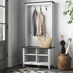 a coat rack with umbrellas and two coats hanging on it's hooks next to a potted plant