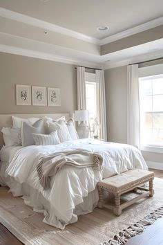 a large white bed sitting in a bedroom next to a wooden table and window sill