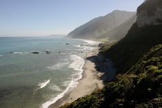 the ocean is clear and blue with waves coming in from the mountains on either side