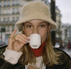 a woman wearing a hat drinking from a cup