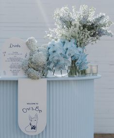 flowers and candles are placed on top of a blue metal container for an outdoor ceremony