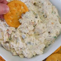 a person dipping crackers into a bowl of dip