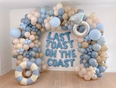 a balloon arch that says last toast on the coast surrounded by balloons and life preservers