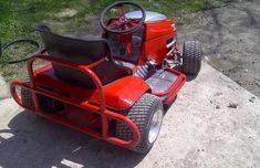 a red lawn mower sitting on top of a cement slab next to a tree