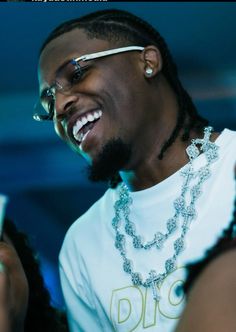 a man with dreadlocks smiles while holding a cell phone