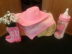 a pink cowboy hat, baby's bottle and cowgirl boots on a table