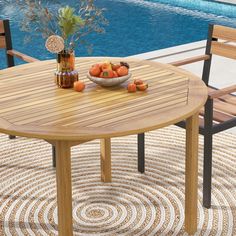 a wooden table sitting next to a pool filled with water and oranges on top of it