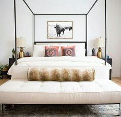 a bedroom with a canopy bed, rugs and pillows on the floor in front of it