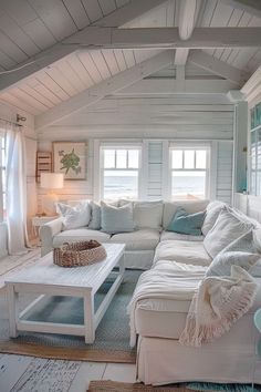 a living room filled with white furniture and lots of pillows on top of it's couches