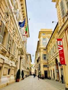 an empty city street with people walking on the sidewalk and flags flying in the air