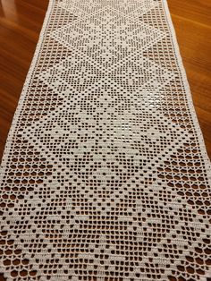 a crocheted table runner on a wooden floor