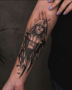 a person with a star wars tattoo on their arm holding onto a hand that has a darth vader in it