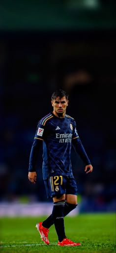 a man standing on top of a soccer field wearing a blue uniform and red shoes