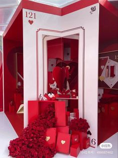 a red and white display case filled with lots of boxes next to flowers on the floor