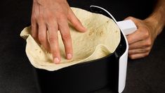 a person holding a tortilla in their left hand and pressing the button on it