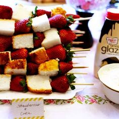 strawberries and marshmallows arranged on skewers next to a bottle of glaze